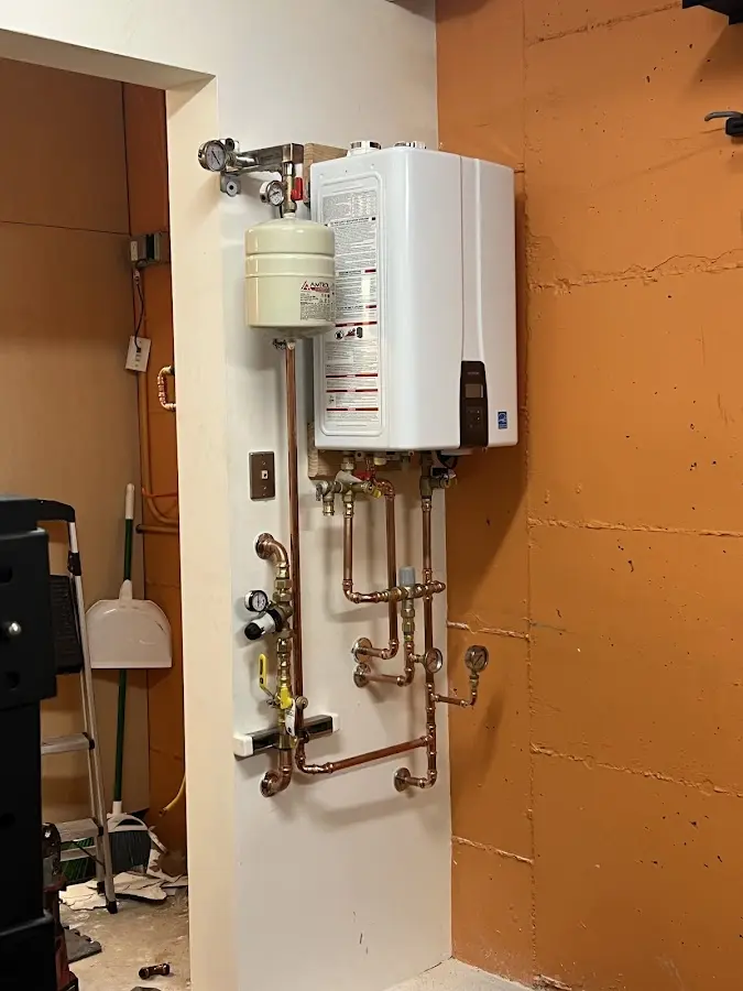 Plumbing technician inspecting water heater connections in Babylon
